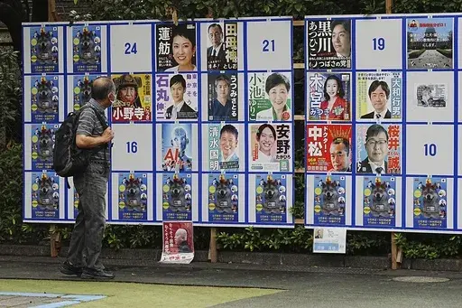 A person looks at an election poster board for Tokyo gubernatorial election Monday, July 1, 2024, in Tokyo. Tokyo elects a new governor on Sunday, July 7, but residents say personal publicity stunts have overtaken serious campaigning to a degree never seen before. There are nearly nude women in suggestive poses, pets, an AI character and a man practicing his golf swing. (AP Photo/Eugene Hoshiko)