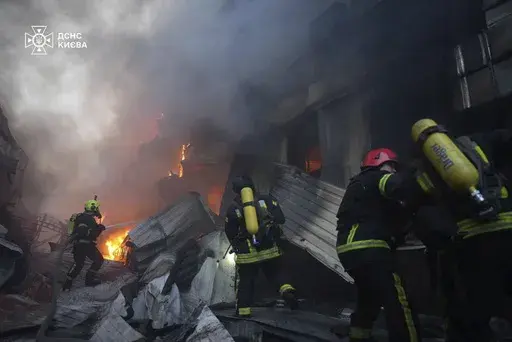 In this photo provided by the Ukrainian Emergency Service, emergency services personnel work to extinguish a fire following a Russian missile attack in Kyiv, Ukraine, Sunday, April 6, 2025. (Ukrainian Emergency Service via AP)