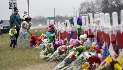 Christina Osborn and her children Alexander Osborn and Bella Araiza visit a makeshift memorial for the victims of the shooting at Sutherland Springs Baptist Church, Nov. 12, 2017, in Sutherland Springs, Texas. The Justice Department said Wednesday, April 5, 2023, that it has tentatively settled a lawsuit over the 2017 mass shooting at a Texas church that will pay victims and their families more than $144 million. (AP Photo/Eric Gay, File)