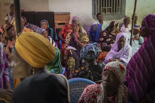 Mourners gather at the house of Ousmane Sylla's mother after his burial in Matoto Bonagui, a suburb of Conakry, Guinea, Tuesday, April 9, 2024. In Italy, he found despair. He spent months in a crowded, squalid migrant detention center, unable to contact his family. He died by suicide in February after other detainees said he became depressed and withdrawn. (AP Photo/Misper Apawu)