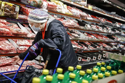 An elderly shopper wears personal protective equipment as she browses the meat section of a grocery store on April 18, 2020, in the Harlem neighborhood of the Manhattan borough of New York. As war, climate change and inequality have consumed much of the 2022 U.N. General Assembly, leaders have largely left unsaid the historic growth of the planet’s aging population. (AP Photo/John Minchillo, File)