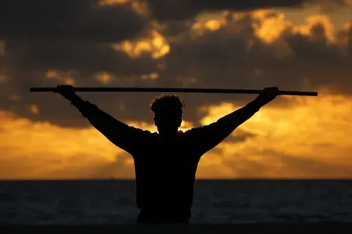 A beach goer exercises as the sun rises above the Atlantic Ocean, Feb. 1, 2023, in Surfside, Fla. (AP Photo/Wilfredo Lee, File)