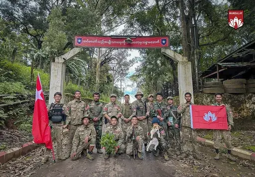 In this photo provided by Mandalay People's Defence Force, its members pose for a photograph in front of the gate of the captured army battalion in Mogok township in Mandalay region, Myanmar, on July 25, 2024. (Mandalay People's Defence Force via AP)