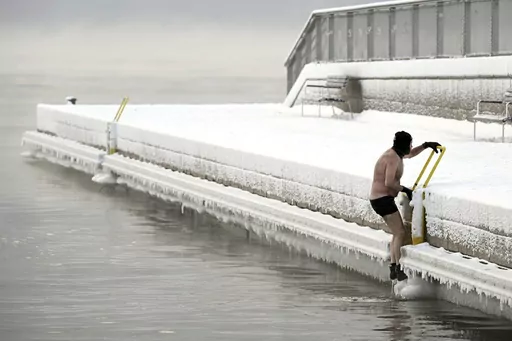 A man climbs out from the icy sea to the pier, in southern Helsinki, Finland, Tuesday, Jan. 2, 2024. Finland and Sweden have recorded this winter’s cold records on Tuesday as a temperatures plummeted to over minus 40 degrees as a result of a cold spell prevailing in the Nordic region. (Vesa Moilanen/Lehtikuva via AP)