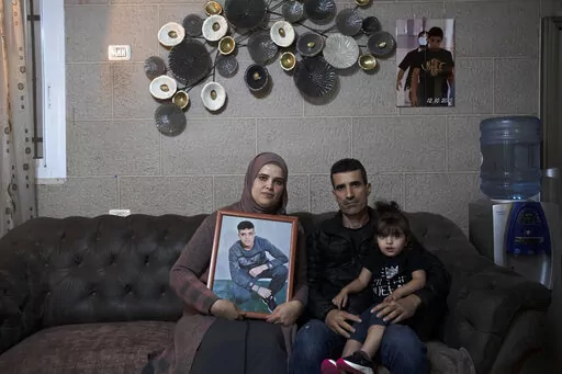 Maysoon, left, and Saleh Manasra, parents of Ahmad Manasra, who has been imprisoned by Israel since he was 13 when he was was convicted of attempted murder and sentenced to nine and a half years in prison, after his older cousin stabbed two Israelis, pose for a portrait with their daughter, Sham, in their home in east Jerusalem, Tuesday, Nov. 8, 2022. The 13 year-old Palestinian boy, whose case became a lighting rod for the Israeli-Palestinian conflict seven years ago, is now a man languishing i