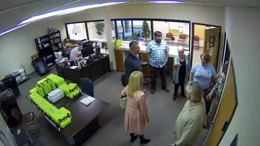 This Jan. 7, 2021, image taken from Coffee County, Ga., security video, appears to show Cathy Latham (center, long turquoise top), introducing members of a computer forensic team to local election officials. Latham was the county Republican Party chair at the time. The computer forensics team was at the county elections office in Douglas, Ga., to make copies of voting equipment in an effort that documents show was arranged by attorney Sidney Powell and others allied with then-President Donald Tr