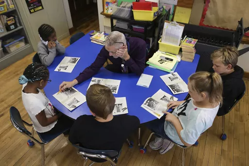 Richard Evans, a teacher at Hyde Park Elementary School, helps Ke'Arrah Jessie sound out a word during a reading circle in class on Thursday, Oct. 20, 2022, in Niagara Falls, N.Y. Evans calls a handful of students back for extra help in reading — a pivotal subject for third grade — at the end of each day. (AP Photo/Joshua Bessex)