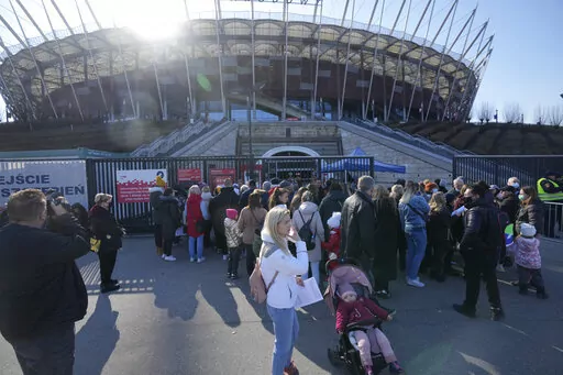 Hundreds of refugees from Ukraine wait in line to apply for Polish ID numbers that will entitle them to work, free health care and education, at a special application point at the National Stadium in Warsaw, Poland, on Saturday, March 19, 2022. The application points are not able to handle all those interested and ask many of them to return. (AP Photo/Czarek Sokolowski)