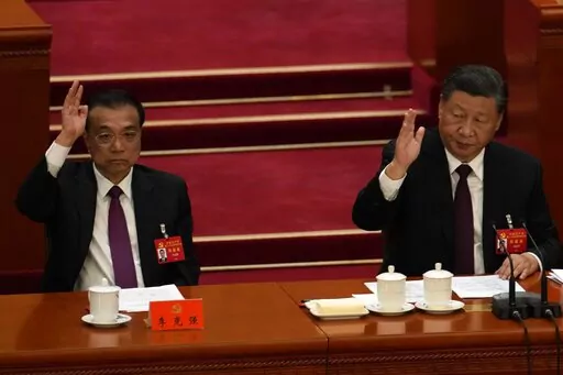 Chinese President Xi Jinping looks over as Chinese Premier Li Keqiang raises his hand to vote at the closing ceremony of the 20th National Congress of China's ruling Communist Party at the Great Hall of the People in Beijing, Saturday, Oct. 22, 2022. Chinese Premier Li Keqiang, the nation's No. 2 official and a chief proponent of economic reforms, is among four of the seven members of the nation's all-powerful Politburo Standing Committee who will not be reappointed in a leadership shuffle Sunda