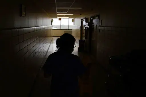 A chief nursing officer walks down a hallway in the recently reopened emergency room at a hospital  in Houma, La., on Friday, Sept. 3, 2021. Patients worried about getting smacked with an unexpected bill after emergency care gained a layer of protection in January 2022 from a new federal law. The No Surprises Act prevents doctors or hospitals in many situations from billing insured patients higher rates because the care providers are not in their insurer’s coverage network. (AP Photo/John Loch