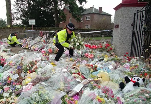 A police officer arranges bouquets of flowers in rows at a side entrance to Dunblane Primary School in Dunblane, Scotland Friday, March 15, 1996. A 1996 school shooting that killed 16 children in Dunblane was Britain's deadliest school shooting — and also the only one. (AP Photo/Lynne Sladky, File)
