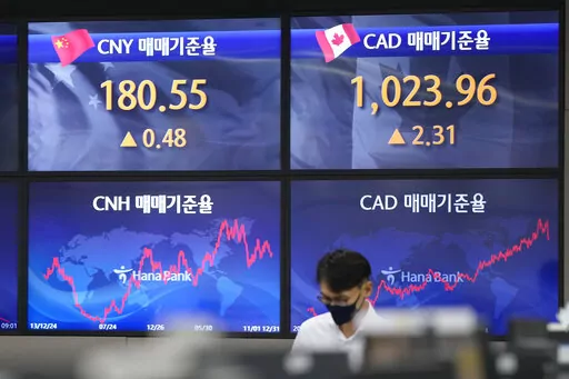 A currency trader walks near the screens showing the foreign exchange rates at a foreign exchange dealing room in Seoul, South Korea, Tuesday, Oct. 11, 2022. Asian shares were mostly lower on Tuesday as losses in technology-related shares weighed on global benchmarks.(AP Photo/Lee Jin-man)
