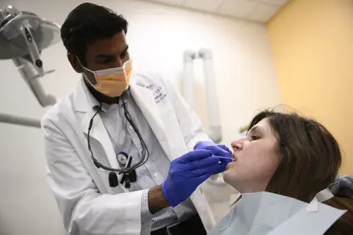 Alexander Daniel, DDS, left, demonstrates fluoride treatment on resident Cameron Onken, right, at the Johns Hopkins Outpatient Center, Friday, Feb. 28, 2025, in Baltimore. (AP Photo/Nick Wass)