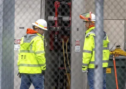 A Tacoma Power crew works at an electrical substation damaged by vandals early on Christmas morning, Sunday, Dec. 25, 2022 in Graham, Wa. (Ken Lambert/The Seattle Times via AP)