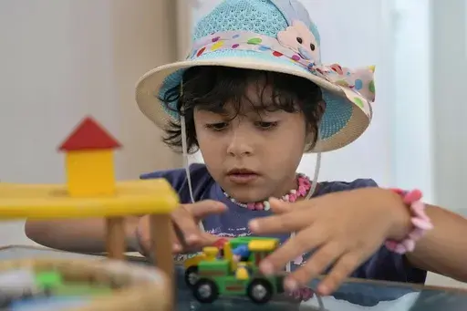 Palestinian girl Halima Abou Yassine, 7, who was brought to Lebanon from Gaza Strip for treatment after an Israeli strike left her near death with a gaping wound in her skull, plays with a toy car at a summer camp in Beirut, Lebanon, Friday, Aug. 30, 2024. (AP Photo/Bilal Hussein)
