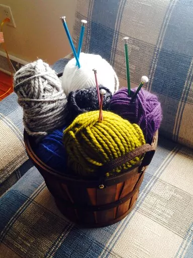 A basket of yarn rests on a couch in Middleborough, Mass. on Sept. 7, 2015. Many people have leaned into crafting, from knitting to beading to adult coloring books, during the pandemic. (AP Photo/Carolyn Lessard)