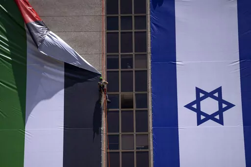 A Palestinian flag is removed from a building by Israeli authorities after being put up by an advocacy group that promotes coexistence between Palestinians and Israelis, in Ramat Gan, Israel, Wednesday, June 1, 2022. In recent weeks, Israeli authorities have gone out of their way to challenge the hoisting of the Palestinian flag. Palestinian citizens of Israel see the campaign against the flag as another affront to their national identity and their rights as a minority in the majority Jewish sta