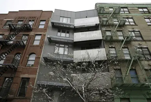 A new building sits between two older-style buildings in the East Harlem section of New York, Feb. 3, 2015. Legislation backed by a majority of the New York City Council would require landlords who hire brokers to pay their broker fees, marking a potential sea change in one of the country’s most expensive housing markets. (AP Photo/Seth Wenig, File)