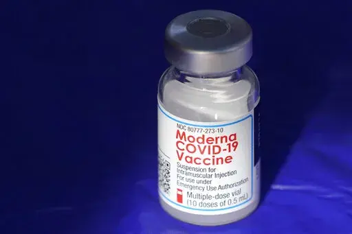 In this March 4, 2021 file photo, a vial of the Moderna COVID-19 vaccine rests on a table at a drive-up mass vaccination site in Puyallup, Wash., south of Seattle.  Moderna’s COVID-19 vaccine brought in nearly $7 billion in the final quarter of 2021, and the drugmaker says it has signed purchase agreements for another $19 billion in sales this year.   (AP Photo/Ted S. Warren, File)