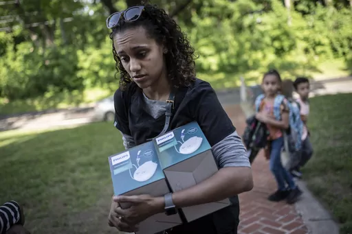 Catherine Manson unloads home nebulizer units from her car while her children, Caydence Manson, center, and Carter Manson, follow behind after they were picked up from school in Hartford, Conn., on Wednesday, May 25, 2022. All three of them suffer from asthma. The children have missed weeks of school, leaving them behind in schoolwork at a critical juncture for their education. And in turn, their parents were forced to miss work to care for them – putting a strain on the family’s finances. (