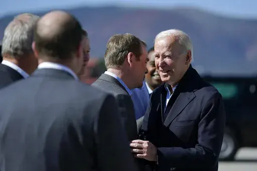 President Joe Biden talks with Sen. Michael Bennet, D-Colo., second from right, as he arrives at Eagle County Regional Airport, in Gypsum, Colo., Wednesday, Oct. 12, 2022, en route to Camp Hale near Leadville, Colo. (AP Photo/Carolyn Kaster)