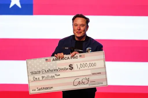Elon Musk speaks at a town hall holding a check Sunday, March 30, 2025, in Green Bay, Wis. (AP Photo/Jeffrey Phelps)
