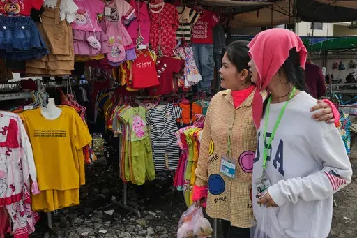 Cambodian garment workers look at clothes displayed for sale during a lunch break on a sidewalk at Ang Tako village, outside Phnom Penh Cambodia, Thursday, April 3, 2025. (AP Photo/Heng Sinith)