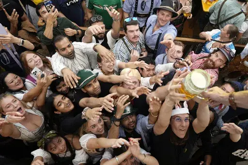 Festival goer reach out for the first glasses of beer at the Hofbraehaus beer tent, on day one of the 189th 'Oktoberfest' beer festival in Munich, Germany, Saturday, Sept. 21, 2024. (AP Photo/Matthias Schrader)