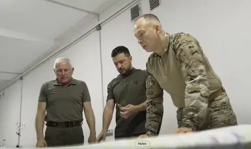 In this photo provided by the Ukrainian Presidential Press Office, Ukrainian President Volodymyr Zelenskyy, center, Commander-in-Chief Oleksandr Syrsky, right, look at a map during their visit to Sumy, Ukraine, Thursday, Aug. 22, 2024. (Ukrainian Presidential Press Office via AP)