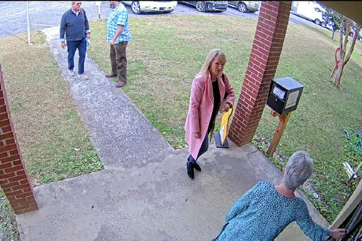 In this Jan. 19, 2021 image taken from Coffee County, Ga., security video, Cathy Latham, bottom, who was the chair of the Coffee County Republican Party at the time, greets a team of computer experts from data solutions company SullivanStrickler at the county elections office in Douglas, Ga. Records show that the team traveled to the rural south Georgia county to copy software and data from elections equipment. The Georgia secretary of state's office has said the visit was an "alleged unauthoriz