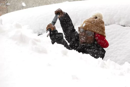 Zaria Black, 24, from Buffalo, clears off her car as snow falls Friday, Nov. 18, 2022, in Buffalo, N.Y.  A dangerous lake-effect snowstorm paralyzed parts of western and northern New York, with nearly 2 feet of snow already on the ground in some places and possibly much more on the way.  (AP Photo/Joshua Bessex)