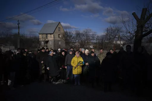 People pay respect as the coffin containing the body of Serhii Havryliuk, 48, passes by during his funeral procession in Tarasivka village, near Kyiv, Ukraine, Wednesday, Feb. 15, 2023. Serhii Havryliuk, an officer of the Azov Assault Brigade, died while defending the Azovstal steel plant in Mariupol on April 12, 2022 against the Russians. Serhii has finally been buried after DNA tests confirmed his identity. (AP Photo/Emilio Morenatti, File)