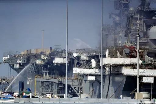 Fire crews spray water from the dock onto the side of the USS Bonhomme Richard, in San Diego, July 12, 2020. No one disputes that the Navy shares blame for the loss of the USS Bonhomme Richard, the $1.2 billion amphibious assault ship that was consumed by flames in San Diego in July 2020 as officers failed to respond quickly and its crew struggled with broken equipment. But none of that would not have happened, according to prosecution closing arguments Thursday, Sept. 29, 2022, without Ryan Saw