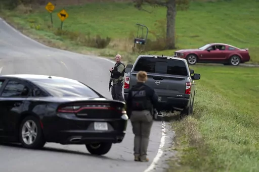 Law enforcement officers hold rifles while investigating a scene, in Bowdoin, Maine, Thursday, Oct. 26, 2023. On Friday, Oct. 27, The Associated Press reported on stories circulating online incorrectly claiming an aerial video of a man lying on his stomach in the middle of a road, being detained by authorities, shows police arresting Maine shooting suspect Robert Card. (AP Photo/Steven Senne, File)
