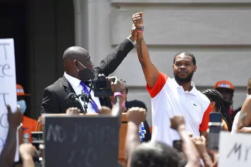 Attorney Benjamin Crump, left, holds up the hand of Kenneth Walker during a rally on the steps of the Kentucky State Capitol in Frankfort, Ky., on June 25, 2020. Walker, the boyfriend of Breonna Taylor who fired a shot at police as they burst through Taylor's door the night she was killed, has settled two lawsuits against the city of Louisville, his attorneys said Monday, Dec. 12, 2022. (AP Photo/Timothy D. Easley, File)