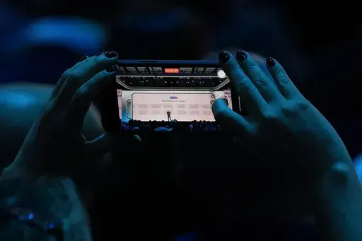 An attendee at the Microsoft Ignite conference records an address on Nov. 19, 2024, in Chicago. (AP Photo/Charles Rex Arbogast, File)