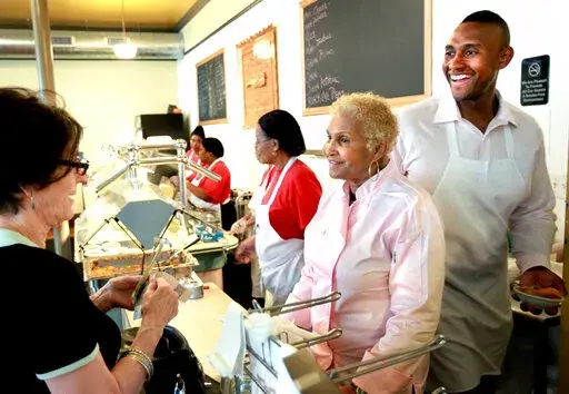 A customer picks up food from Sweetie Pie's owner Robbie Montgomery, second right, and Montgomery's son, James "Tim" Norman, right, at the shop in St. Louis, on April 19, 2011. A St. Louis jury on Friday, Sept. 16, 2022, convicted Norman, a former star of the reality TV show “Welcome to Sweetie Pie’s,” of arranging the shooting death of his nephew. (David Carson/St. Louis Post-Dispatch via AP, File)
