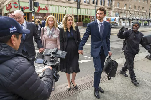 Theranos founder and CEO Elizabeth Holmes, center, walks into federal court in San Jose, Calif., Nov. 18, 2022. Holmes is citing her recently born child as another reason she should be allowed to delay the start of a more than 11-year prison sentence while her lawyers appeal her conviction for duping investors about the capabilities of her failed company's blood-testing technology. The birth of Holmes' second child was confirmed in court documents filed Thursday, Feb. 23, 2023, in advance of a M