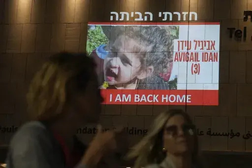 People walk past an image of 4-year-old Abigail Edan, a hostage held by Hamas, projected onto a building in Tel Aviv, Nov 26, 2023. Edan's parents were both killed by Hamas militants in the same attack in which she was kidnapped, a cross-border assault Oct. 7 that prompted Israel to declare war on Hamas. President Joe Biden has met at the White House with Abigail Edan. (AP Photo/Ariel Schalit, File)