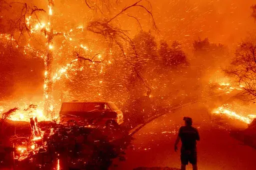 Bruce McDougal watches embers fly over his property as the Bond Fire burns through the Silverado community in Orange County, Calif., on Dec. 3, 2020. New research shows climate misinformation has been flourishing on Twitter since Elon Musk purchased the platform in 2022. (AP Photo/Noah Berger, File)