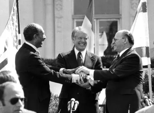 Egyptian President Anwar Sadat, left, U.S. President Jimmy Carter, center, and Israeli Prime Minister Menachem Begin clasp hands on the north lawn of the White House after signing the peace treaty between Egypt and Israel on March 26, 1979, in Washington. (AP Photo/ Bob Daugherty, File)