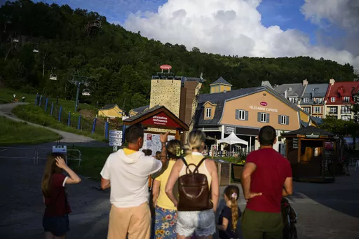 People look at the Express gondola at Mont-Tremblant Resort, temporarily closed after one person died and another was critically injured after a gondola crashed into a piece of construction equipment, in Mont-Tremblant, Quebec, on Sunday, July 16, 2023. (Justin Tang/The Canadian Press via AP)