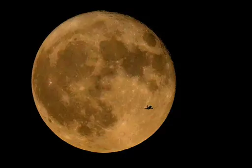 A commercial airliner flies Northwest across Lake Michigan in front of the "Full Buck" supermoon, the first of four supermoons in 2023, July 3, 2023, in Chicago. The cosmos is offering up a double feature in August: a pair of supermoons. Catch the first show Tuesday night, Aug. 2, as the full moon rises in the southeast. (AP Photo/Charles Rex Arbogast, File)