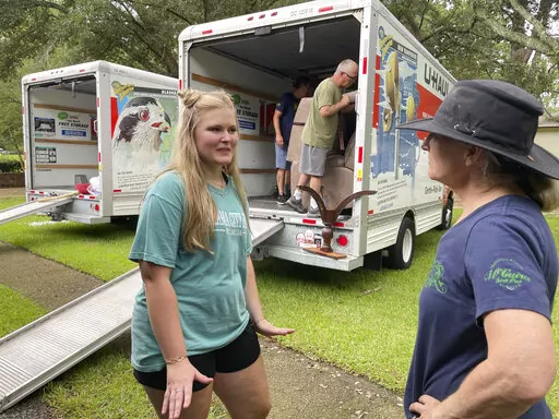 Medical student Emily Davis, left, speaks with her landlord Suzannah Thames on Friday, Aug. 26, 2022, as workers move furniture, appliances and other belongings out of a home Davis and her husband are renting in a flood-prone area of Jackson, Miss. After heavy rainfall, the Pearl River near Jackson is expected to flood some homes and businesses by Tuesday, Aug. 30, 2022. (AP Photo/Emily Wagster Pettus)