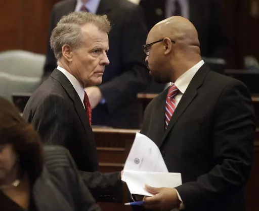 Illinois Speaker of the House Michael Madigan, D-Chicago, left, speaks with Illinois Rep. Thaddeus Jones, D-Calumet, right, while on the House floor, Nov. 7, 2013, in Springfield Ill. On Monday, Nov. 6, 2023, officials in a suburban Chicago community dropped municipal citations against Hank Sanders, a local news reporter, for what they said were persistent contacts with city officials seeking comment on treacherous fall flooding. Sanders continued to report on the issue, drawing complaints from 