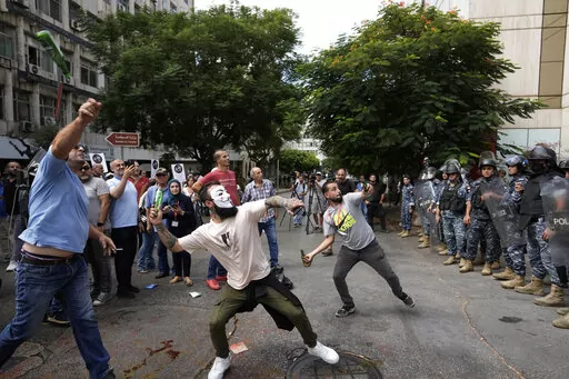 Protesters throw bottles glasses at the Lebanese Central Bank building, background, where the anti-government demonstrators rally against the Lebanese Central Bank Governor Riad Salameh and the deepening financial crisis, in Beirut, Lebanon, Wednesday, Oct. 5, 2022. Lebanon's once burgeoning banking sector has been hard hit by the country's historic economic meltdown, suffering staggering losses worth tens of billions of dollars and leaving the future of the small nation's lenders unknown betwee