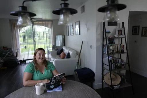 Melissa Lombana, 43, a high school teacher and mountain bike enthusiast, poses for a picture while working online, in her one-bedroom apartment in Miramar, Fla., Wednesday, July 26, 2023. Lombana's rent has increased each of the last two years and now amounts to nearly half her monthly income. "In a year, I will not be able to afford living here at all," she said. (AP Photo/Rebecca Blackwell)