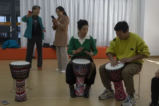 Cai Guixia, 60, second from right, learns African drumming from an instructor at the University for the Elderly in Beijing, Oct. 23, 2024. (AP Photo/Ng Han Guan)