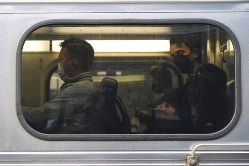 People wear face masks as they sit in a Metra train at the Metra Arlington Heights station Thursday, Sept. 15, 2022, in Arlington Heights, Ill. President Joe Biden said Thursday a tentative railway labor agreement has been reached, averting a potentially devastating strike before the pivotal midterm elections. (AP Photo/Nam Y. Huh)