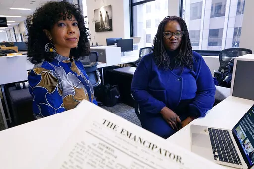 Amber Payne, left, and Deborah Douglas co-editors-in-chief of the new online publication of "The Emancipator" pose at their office inside the Boston Globe, Wednesday, Feb. 2, 2022, in Boston. Boston University's Center for Antiracist Research and The Boston Globe's Opinion team are collaborating to resurrect and reimagine The Emancipator, the first abolitionist newspaper in the United States, which was founded more than 200 years ago. The new incarnation of The Emancipator will explore ways to r